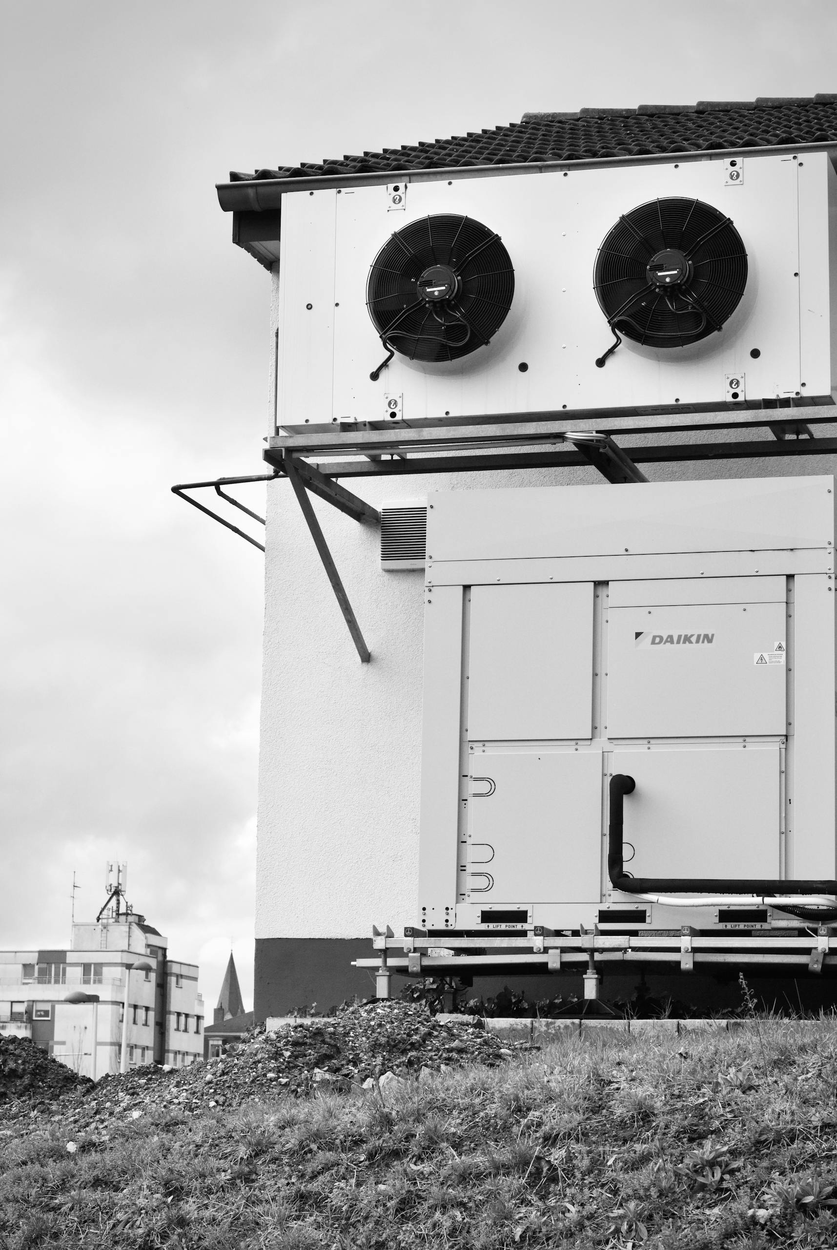 Black and white photo of industrial HVAC units on building, showcasing architecture and machinery.