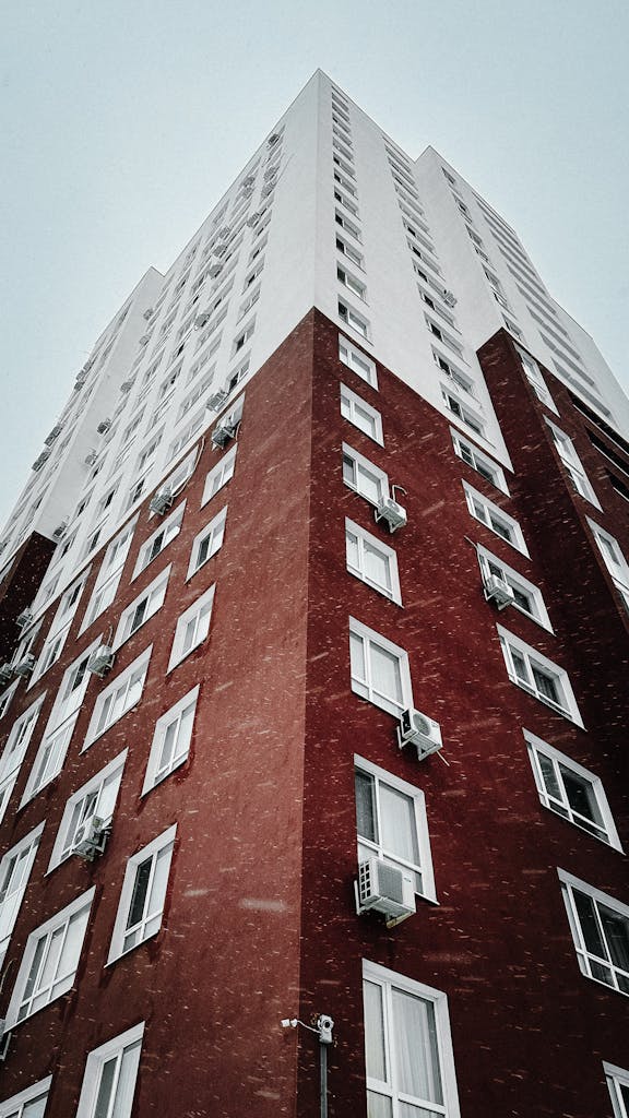 Upward view of a tall brick residential building during a snowy winter day.