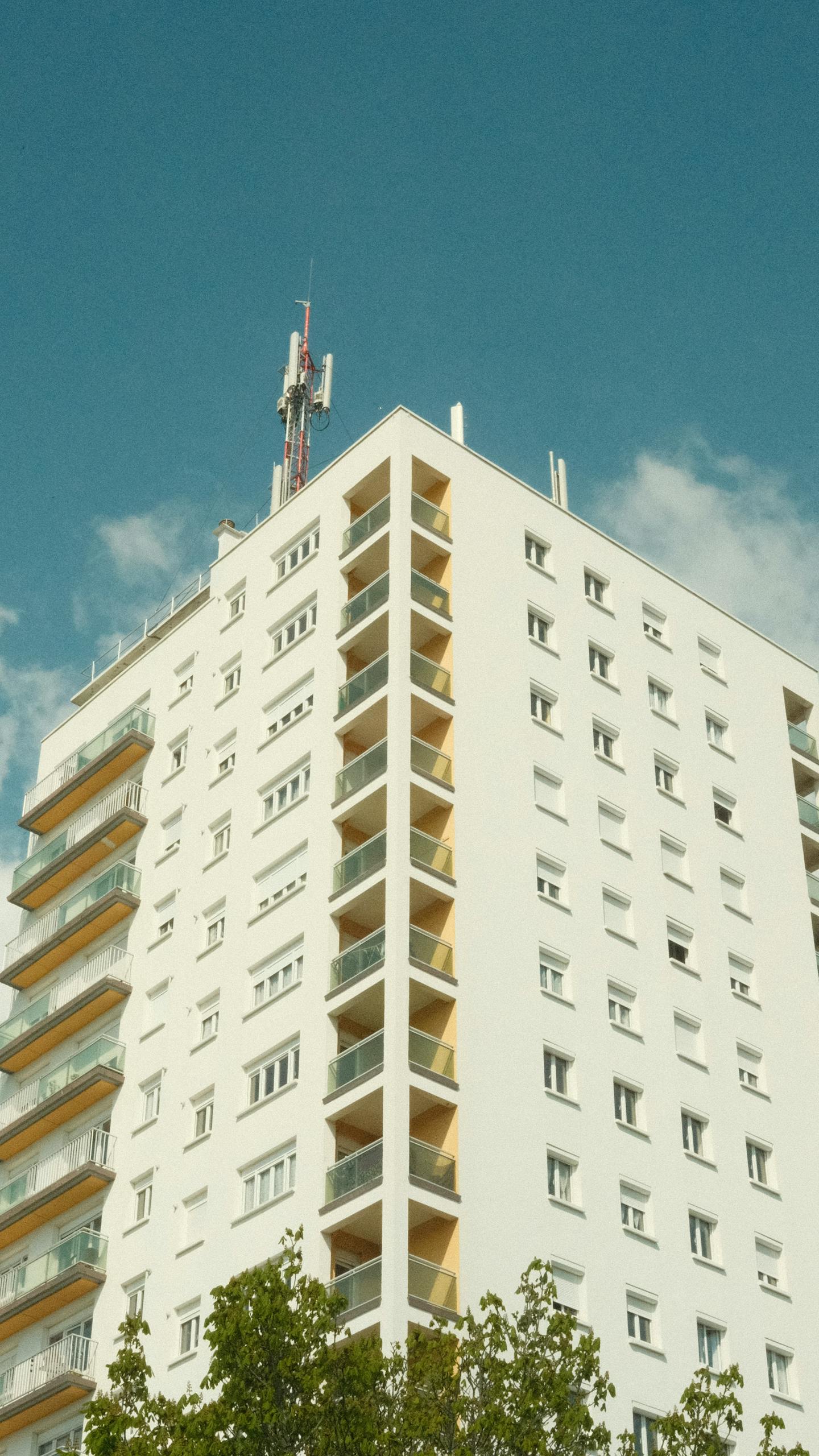 Vertical shot of a sunlit urban apartment building with blue sky background.